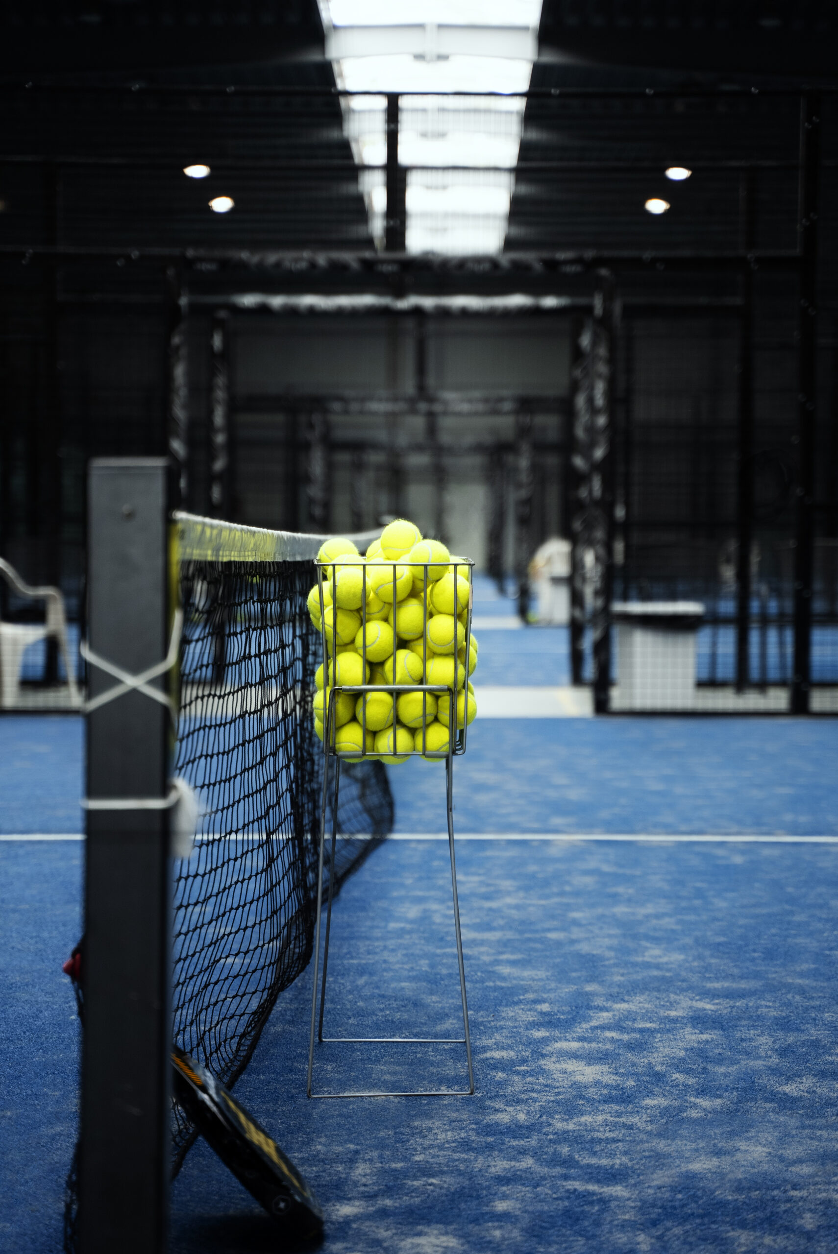 A basket of padel balls on an indoor court