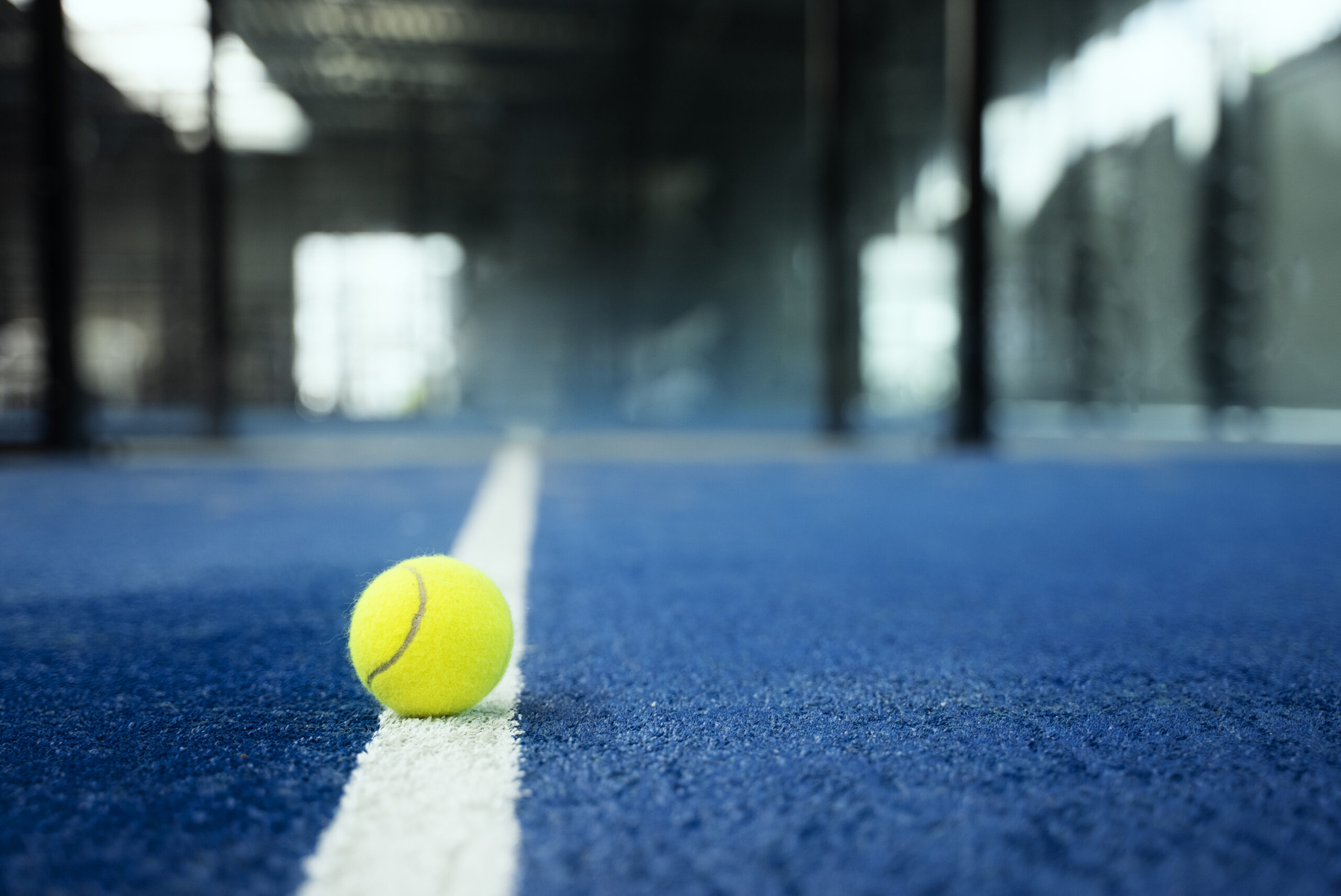 A padel ball resting on the court line